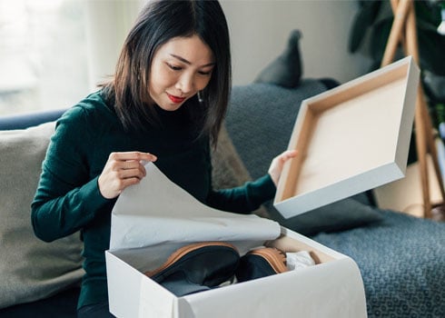 Woman opening box with a pair of shoes she ordered. 