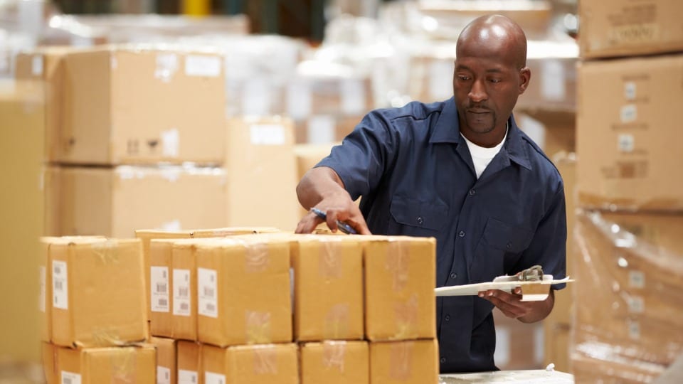 Male worker in warehouse preparing goods for dispatch