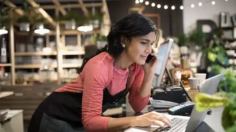 Femme au téléphone qui utilise un ordinateur portable