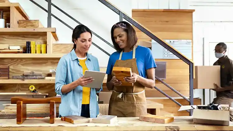 Two women discussing delivery in their office while sending shipments