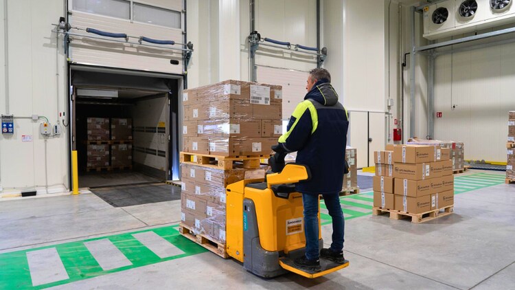 employee in facility moving boxes with forklift